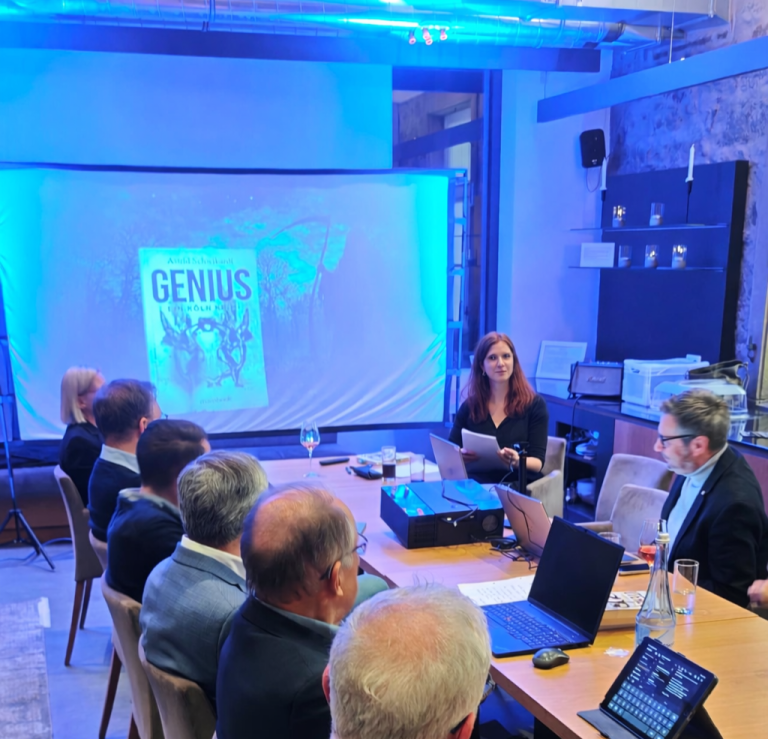 Besprechung in einem modernen Raum, Fokus auf eine Frau, die vor einem Projektor spricht.