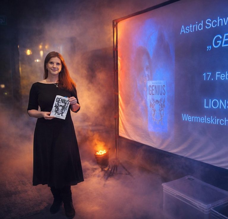Astrid Schwikardi in schwarzem Kleid hält ihren Kriminalroman Genius vor einer beleuchteten Leinwand mit Nebel.