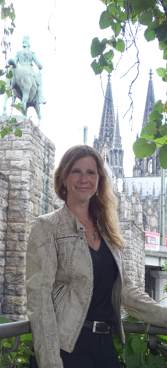Frau mit langen Haaren vor einer Stadtlandschaft mit dem Kölner Dom