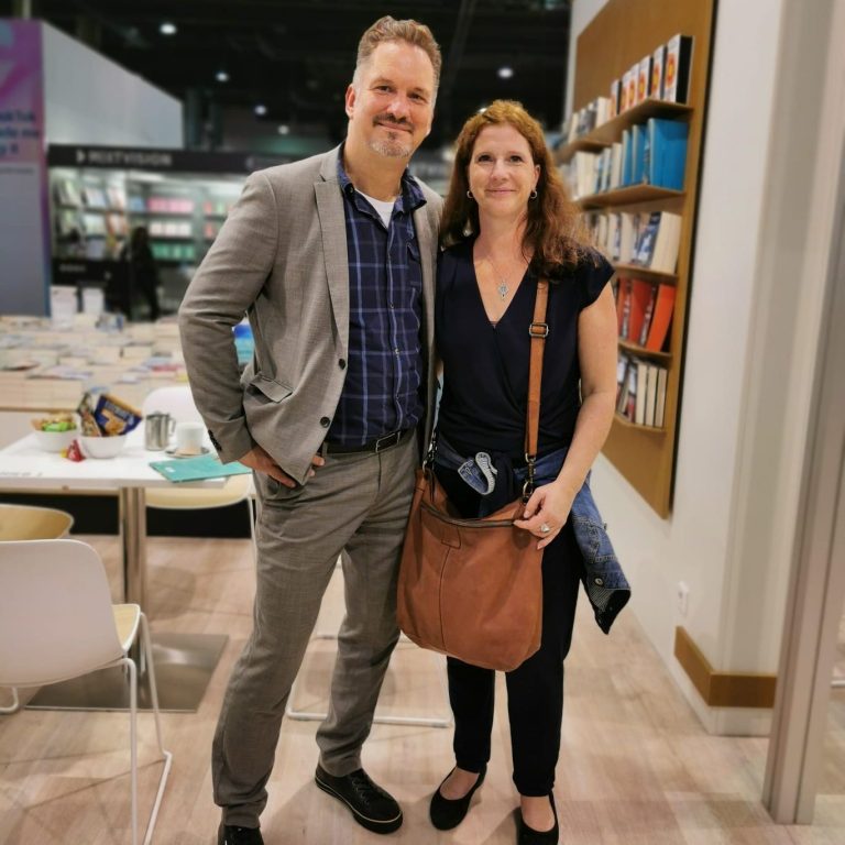 Ein Mann und eine Frau stehen lächelnd in einer Buchhandlung.