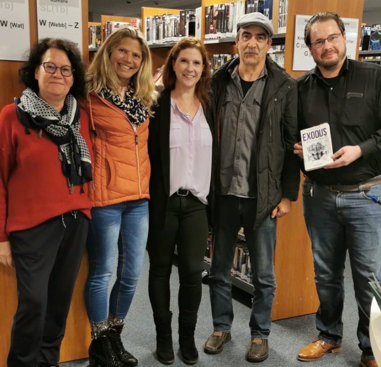 Fünf Personen in einem Buchgeschäft stehen zusammen und lächeln in die Kamera.