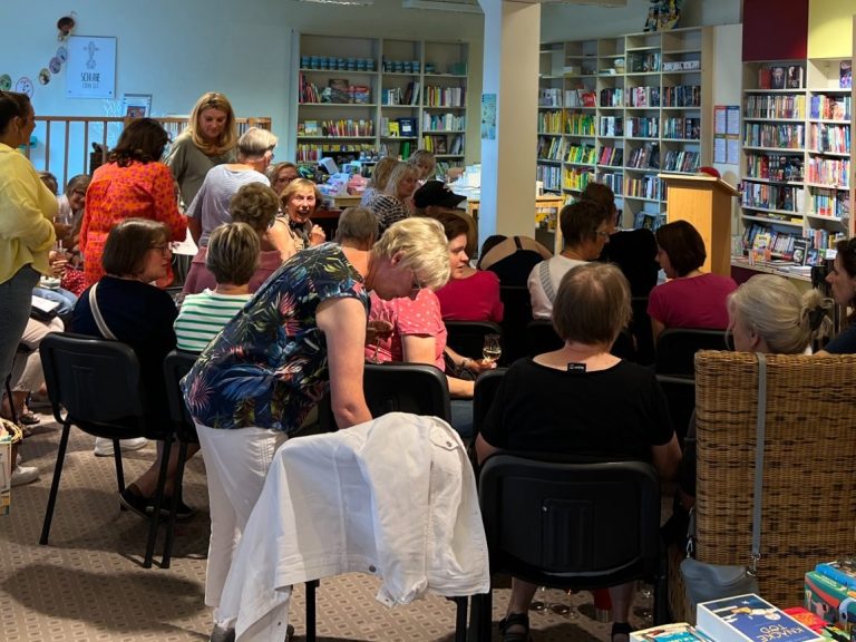 Eine Gruppe von Menschen sitzt in einem Raum, umgeben von Büchern und Regalen.