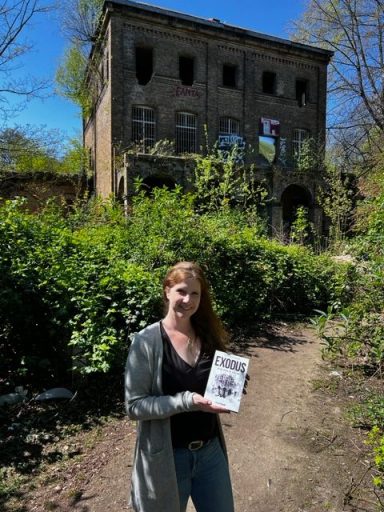 Astrid Schwikardi mir ihrem Kriminalroman Exodus vor einem verlassenen Haus